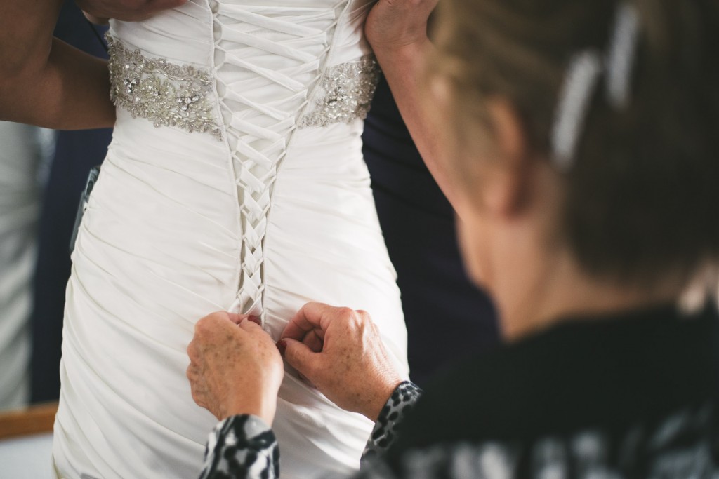 Lacing up wedding dress  with Tom Studios Wedding Photography